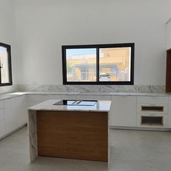 מטבח לבן עם אי שיש קררה ובסיס עץ אלון