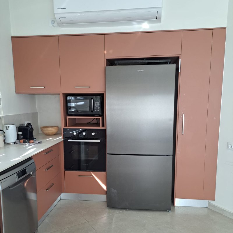 מטבח בגוון טרקוטה עם מקרר ותנור משולבים בתוך הארונות